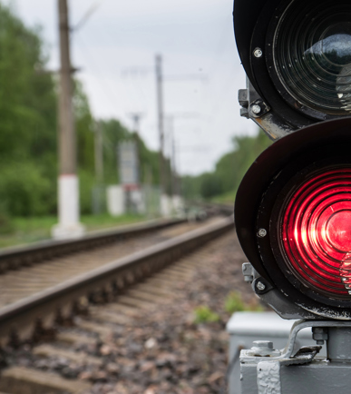 Rote Ampel mit Bahngeleisen im Hintergrund